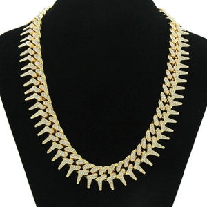 Detail of gold-tone spiked hip-hop necklace with diamonds on a black mannequin