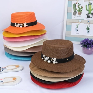 Detail of woven straw hats with pearl flower accents and elegant black ribbon decor
