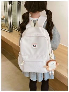 Detail of cream kids backpack with cute cat logo and funny toast bread pendant