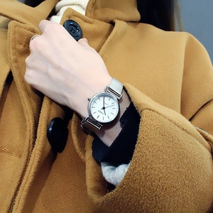 Close-up of a silver Milanese strap watch on wrist with a classic white round dial
