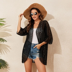 Detail of black crochet lace beach cover-up showing delicate hollow weave texture