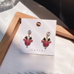 Detail of cute red reindeer earrings with gold base and zircon on a jewelry card