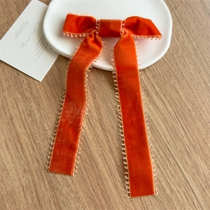 Détail d'un nœud à cheveux en velours orange avec bordure crochetée sur bois