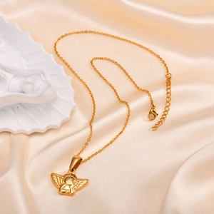 Detailed view of an embossed gold angel pendant on a sleek chain over silk background