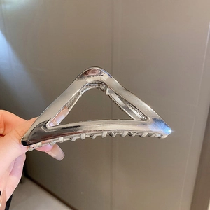 Close-up of a large silver triangular metal hair claw clip with a hollow geometric design