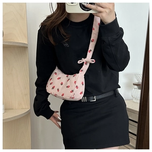 Close-up of pink corduroy shoulder bag with strawberry prints and bow strap detail