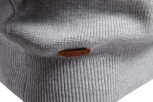 Detail of gray knitted fabric with a brown leather patch and embossed AIO PESON logo