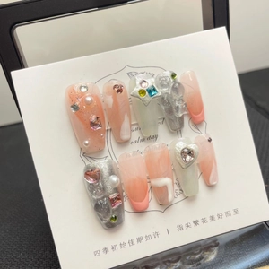 Detail of handmade press-on nails featuring pink gradient, rhinestones and pearls