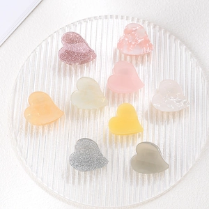 Detailed view of eight mini heart hair claws in various colorful marble and glitter finishes