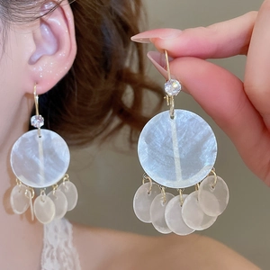 Detail of vintage round mother of pearl tassel earrings with zircon studs on a model