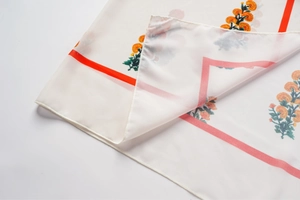 Gros plan sur un tissu mousseline semi-transparent aux motifs floraux et bordure orange