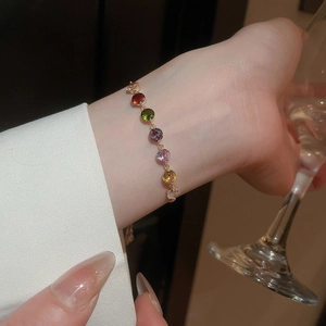 Close-up of golden pull-bracelet with colorful zircons on woman's wrist in elegant setting
