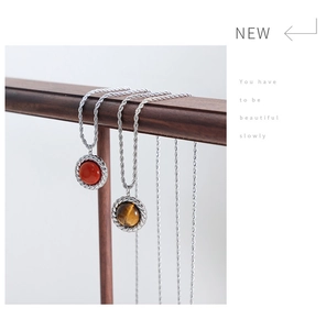 Detail of round tiger eye and red jasper stone pendants on silver cable chain necklace