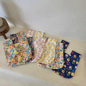 Detailed view of stacked vintage floral canvas wristlet bags in various patterns and colors