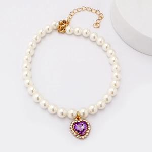 Detailed close-up of a pearl pet necklace with a purple heart gemstone and gold chain