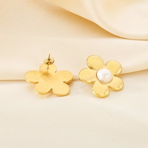 Close-up of gold flower earrings with pearl inlay on an elegant beige silk background