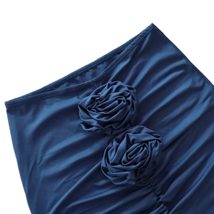 Detailed view of deep blue skirt featuring 3D fabric roses and elegant side pleats