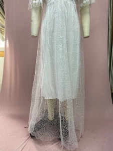 Close-up of white mesh wedding dress featuring intricate floral lace and sequins