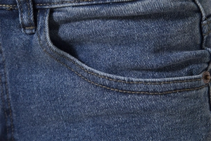 Macro detail of blue denim jeans pocket with durable stitching and metal rivets
