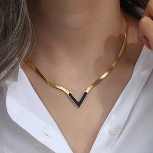 Detailed view of a gold V-shaped pendant with black inlay on a flat snake chain