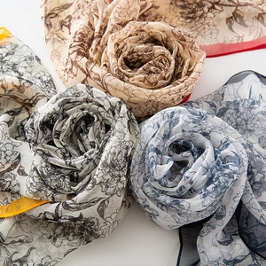 Three elegant printed georgette scarves rolled into rose shapes on white background