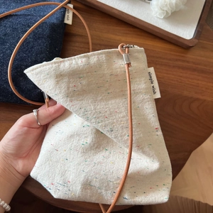 Detail showing mini fabric crossbody bags with leather cord straps and side label