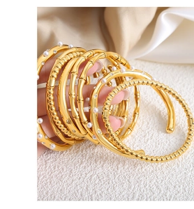 Detail of gold bamboo texture bangle with pearls and zircon set on satin background