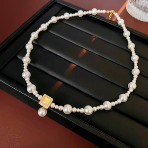 Detailed close-up of 18k gold plated irregular necklace with pearls and rhinestone pendant