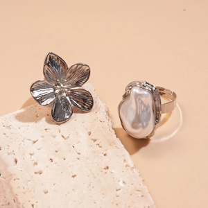 Detailansicht von zwei silbernen Ringen mit Blumenmotiv und unregelmäßiger Perle