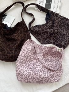 Three leopard print canvas tote bags in different shades laid on a white bed sheet