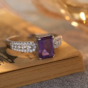 Macro view of rectangular amethyst silver ring placed on a vintage book with bokeh background