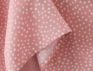 Detailed macro shot of pink polka dot lace fabric with high-quality stitching and texture