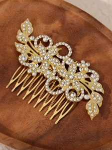 Detailansicht goldener Brauthaarkamm mit Strasssteinen auf einem Holztablett