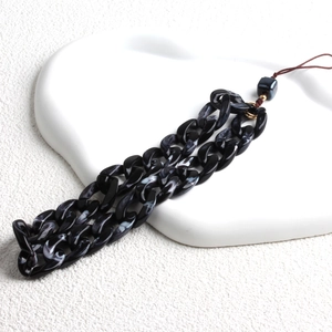 Close-up of black and white marble acrylic phone chain with gold rings and brown cord