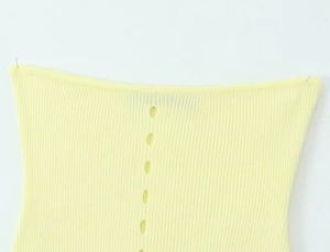 Primer plano de tejido de punto amarillo claro con detalles decorativos calados verticales
