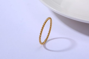 Nahaufnahme eines 18K vergoldeten Kordelrings auf einer schlichten weißen Fläche
