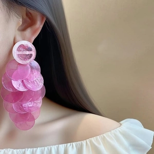 Detail of pink tiered shell pendant earrings with designer logo stud on model