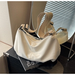 Detail of minimalist cream beige nylon tote bag with wide strap on magazine background