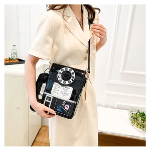 Model wearing a retro telephone crossbody bag in black patent leather for street style