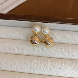 Detailed macro view of white pearl and gold ball earrings inside a luxury jewelry box