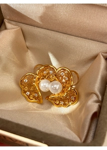 Macro view of gold petal earrings with white pearls and diamonds on champagne satin