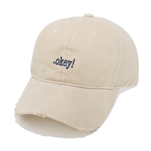 Close-up of blue okey embroidery and distressed brim on beige cotton baseball cap