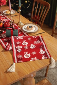 Detail of red Christmas table runner with knitted snowflake patterns and white tassels