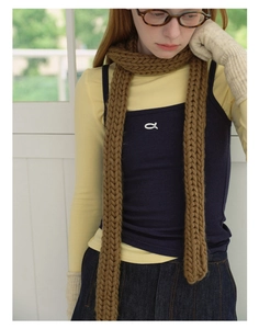 Detailed view of brown chunky knit scarf paired with beige gloves and navy vest