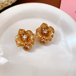 Detail of vintage flower earring with amber enamel petals and gold pearl drop