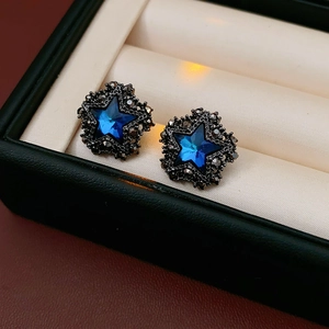 Nahaufnahme sternförmiger Ohrstecker mit blauem Kristall und schwarzen Zirkoniasteinen