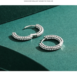 Detailed side view of silver hoop earrings featuring micro-engraved heart cutouts and zircons