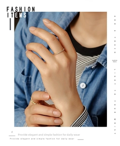 Detail of twisted gold-plated rope ring styled for stacking on a finger