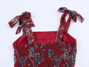 Détail d'une robe en mousseline fleurie rouge foncé avec bretelles à nouer et fronces