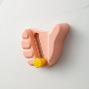 Pink thumb-shaped multi-purpose wall hook for mop and broom organization in bathroom